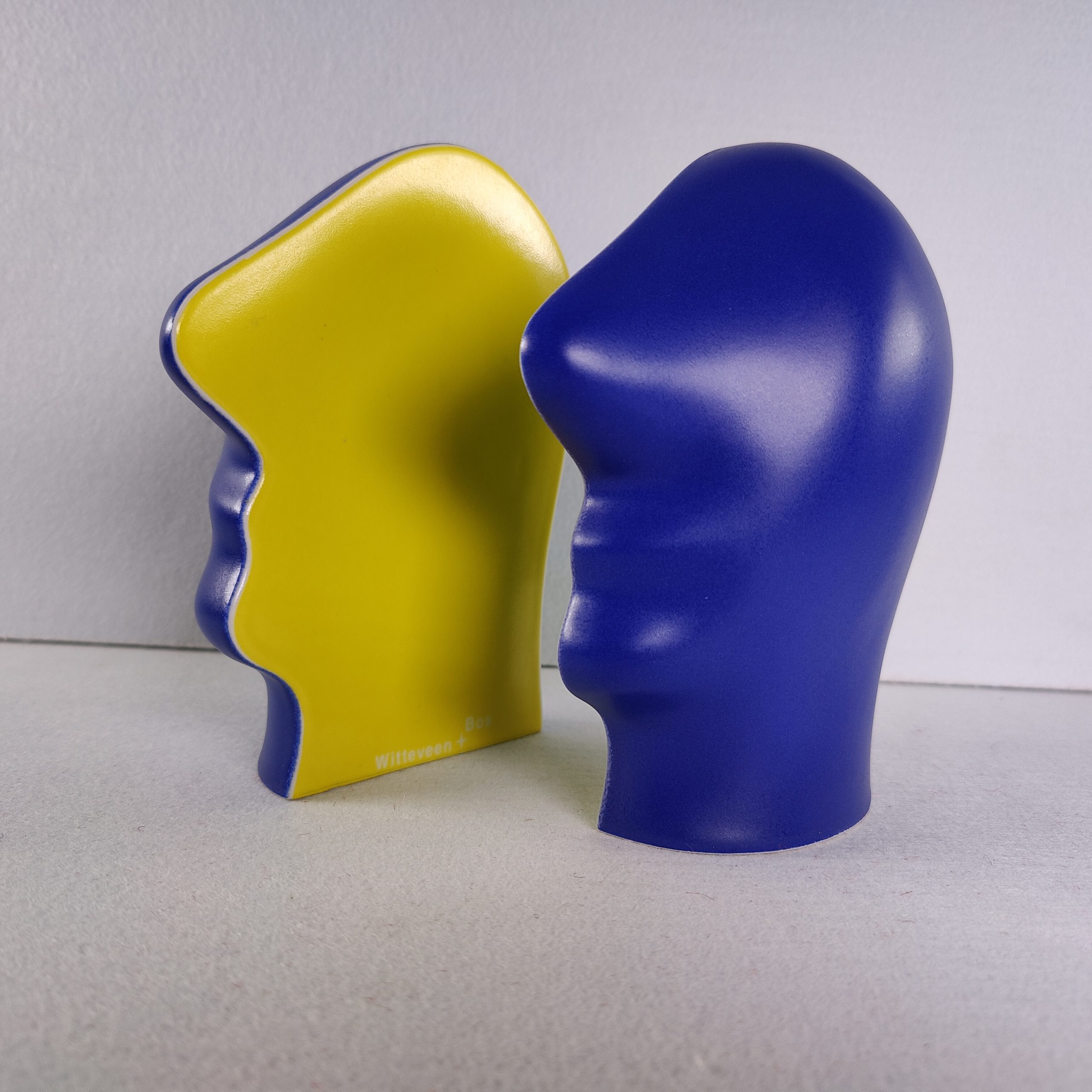 Kunstwerk "Split Personality" van Jan Snoeck in driekwart aanzicht, met het gele en het blauwe keramische hoofd naast elkaar.