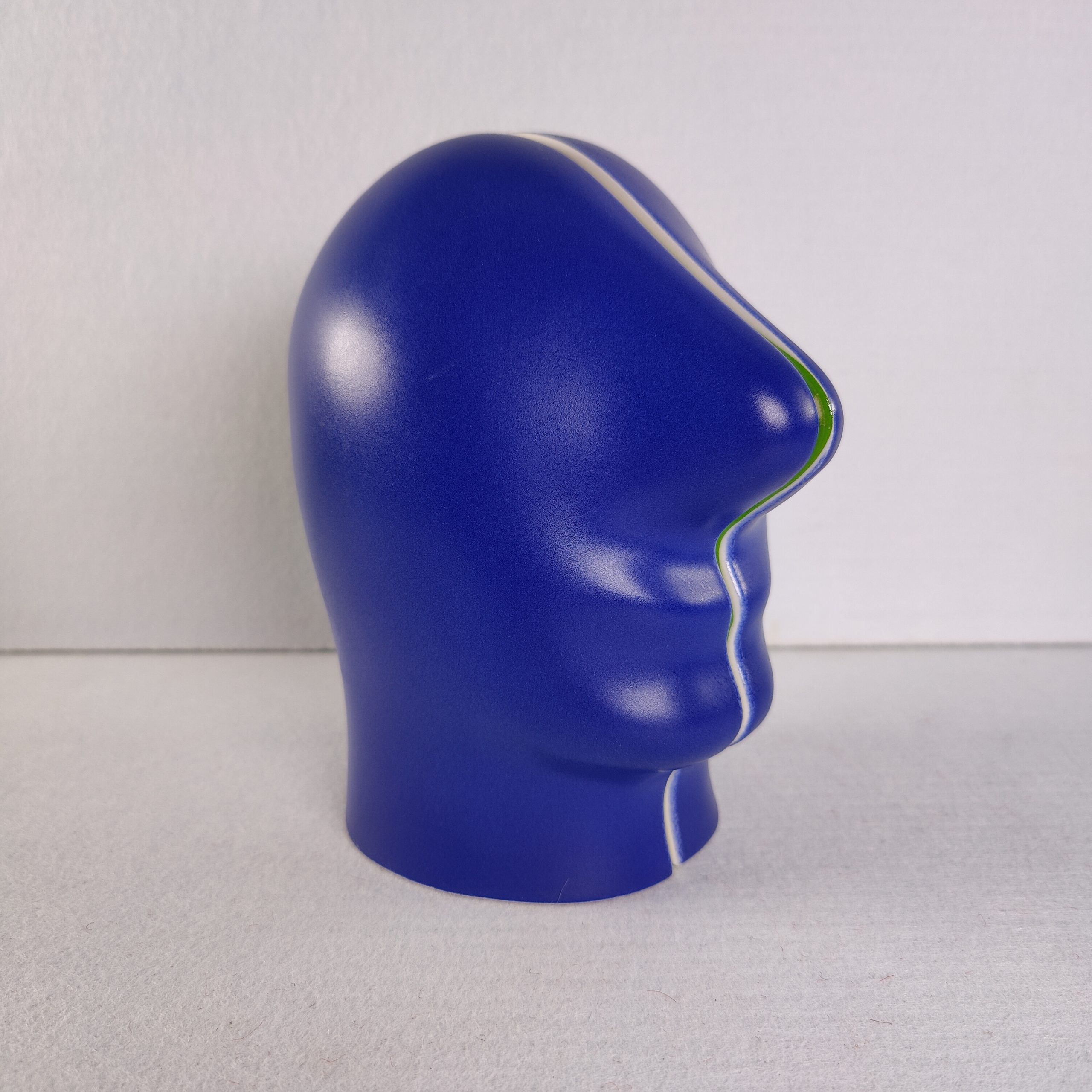 Zijaanzicht van het blauwe keramische hoofd van Jan Snoeck, met een gekleurde naad in groen en geel langs het gezichtsprofiel.