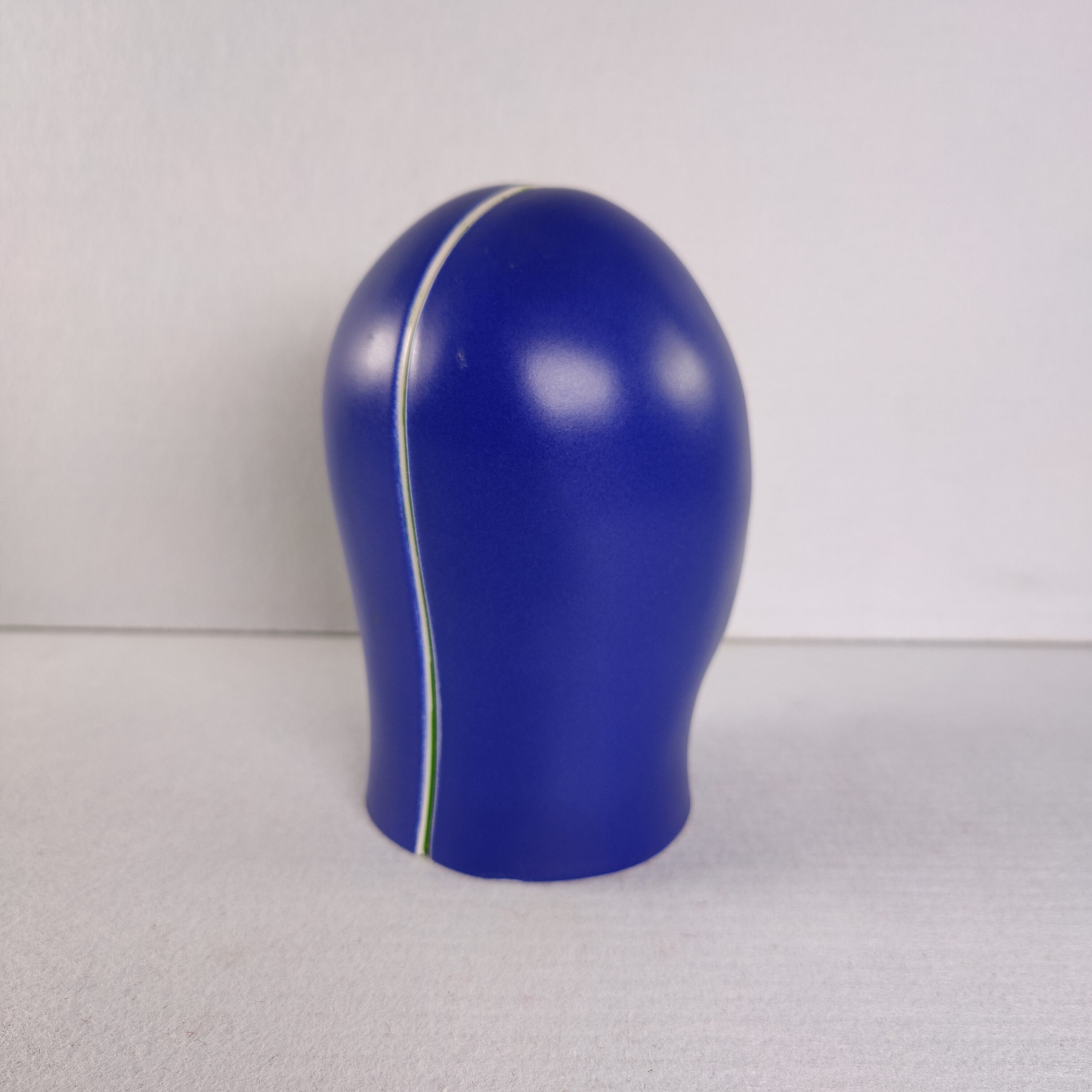 Achterzijde van het blauwe keramische hoofd van Jan Snoeck, met een dunne gele en groene kleurlijn over de schedel.