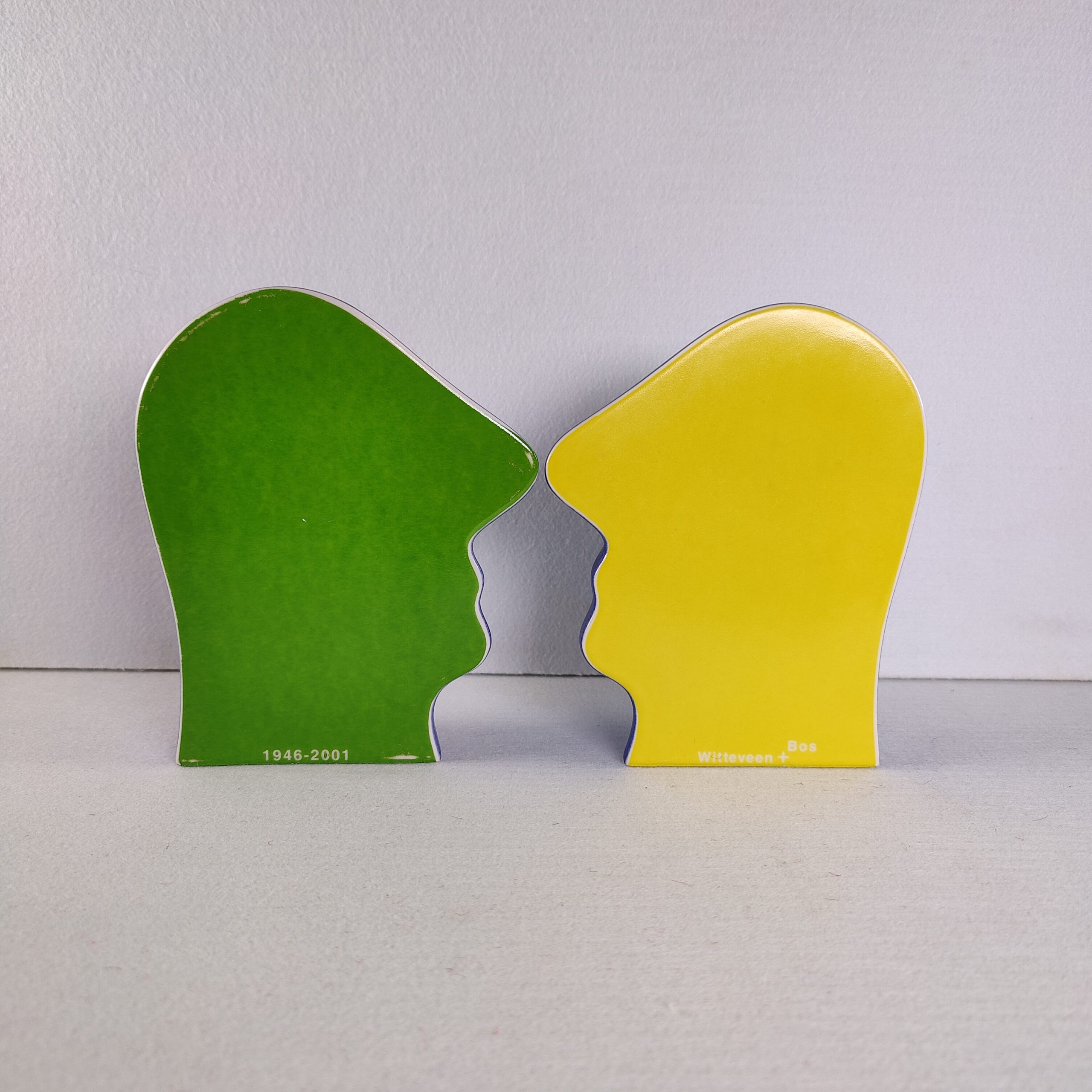 De twee platte profielzijden van "Split Personality" tegenover elkaar, links groen en rechts geel, met de teksten 1946-2001 en Witteveen + Bos.